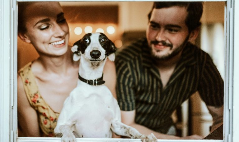 Ein Mann und eine Frau mit einem Hund auf dem Schoß, der große Augen macht